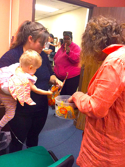 A mother and her baby are reaching for candy.